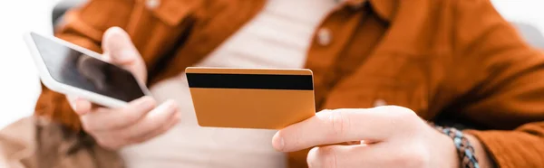 Vista cortada de artista 3d segurando cartão de crédito e smartphone isolado em branco, tiro panorâmico — Fotografia de Stock