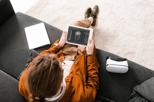 Vista aérea de la tableta digital del sostenimiento del diseñador con el proyecto del diseño 3d cerca del ordenador portátil y del auricular del vr en el sofá — Stock Photo