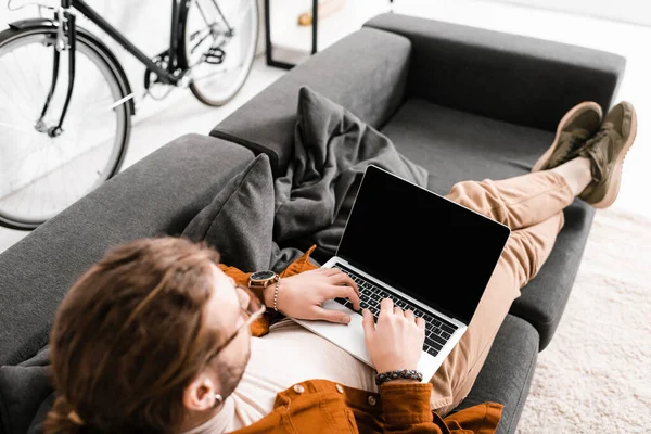 Overhead view of 3d artist using laptop with blank screen on couch in office — Stock Photo