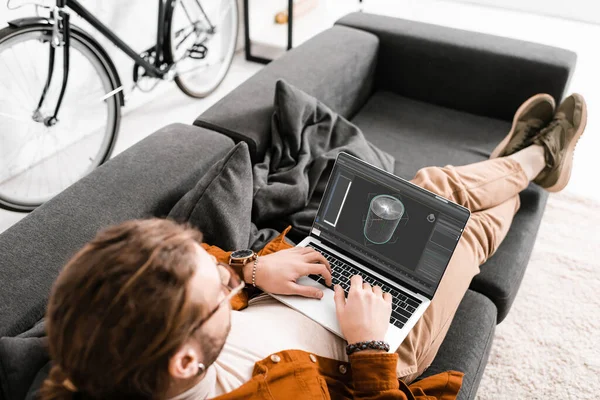 Vue aérienne du concepteur numérique travaillant avec un projet de conception 3D sur un ordinateur portable sur un canapé dans un bureau — Photo de stock