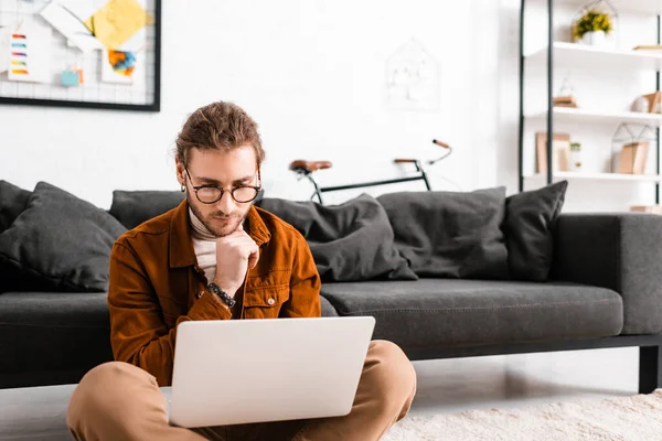 Beau concepteur numérique travaillant sur ordinateur portable sur le sol dans le bureau — Photo de stock