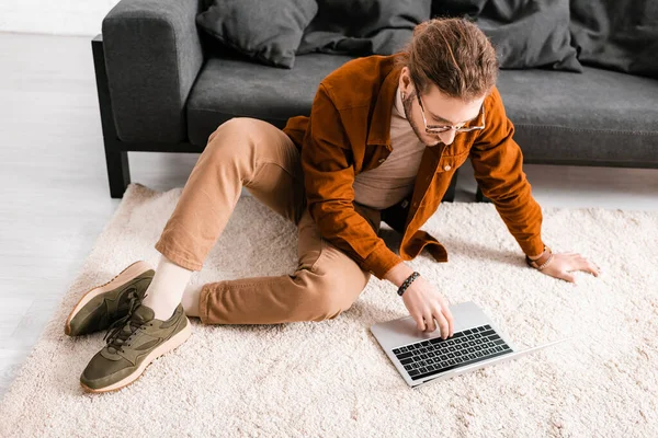 3d artist working on laptop while sitting on floor in office — Stock Photo