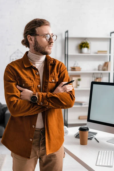 Handsome 3d artist holding stylus of graphics tablet near digital devices on table — Stock Photo