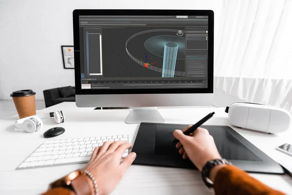 Vista recortada del diseñador digital utilizando gráficos tableta y teclado de la computadora mientras se trabaja en el proyecto de diseño 3D en la mesa - foto de stock