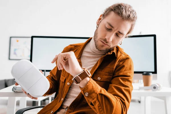 Красивый 3D художник смотрит на наручные часы и держа гарнитуру в офисе — стоковое фото