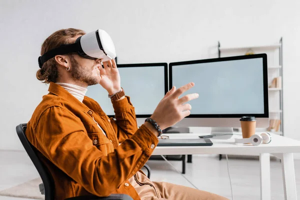 Side view of 3d artist gesturing while using vr headset near digital devices on table — Stock Photo