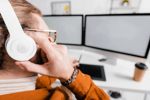 Foco seletivo do artista 3d ouvindo música enquanto renderiza projeto em computadores no escritório — Fotografia de Stock