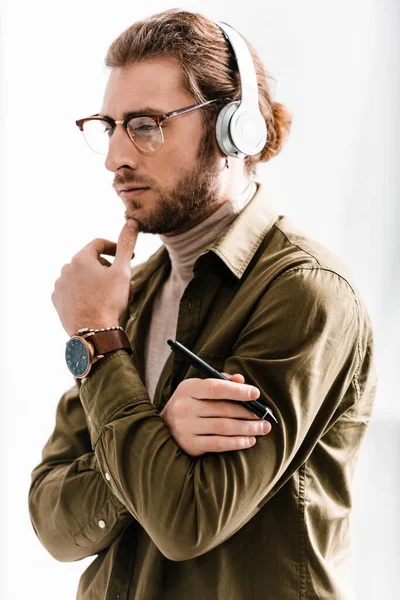 Nachdenklicher 3D-Künstler mit Kopfhörer, der den Stift des Grafik-Tablets in der Hand hält und auf grauem Hintergrund wegschaut — Stockfoto