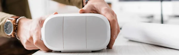 Cropped view of 3d artist taking virtual reality headset from table, panoramic shot — Stock Photo