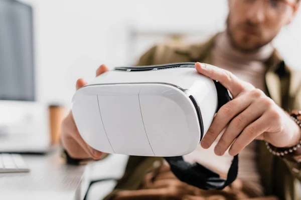 Вибірковий фокус 3d художника, який тримає гарнітуру віртуальної реальності за столом — стокове фото