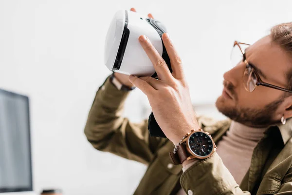Selective focus of handsome 3d artist looking virtual reality headset in office — Stock Photo