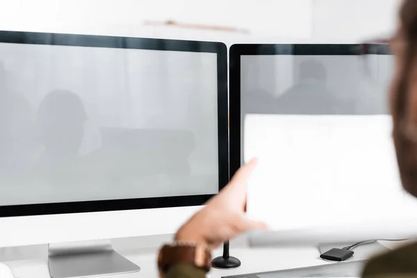 Selective focus of 3d artist holding blueprint near computer monitors on table — Stock Photo