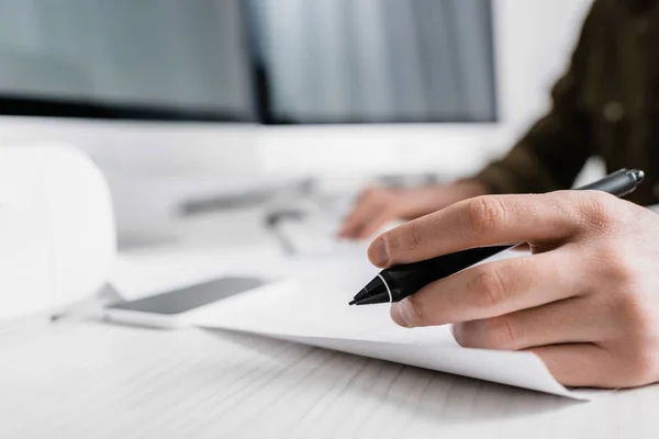 Vista recortada de artista 3d sosteniendo lápiz de gráficos tableta cerca de papel en la mesa — Stock Photo