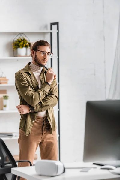 Bello artista 3d che tiene lo stilo del tablet digitale e guarda i monitor del computer sul tavolo in ufficio — Foto stock