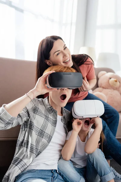 Impresionado niño usando auriculares vr con madres en la sala de estar - foto de stock