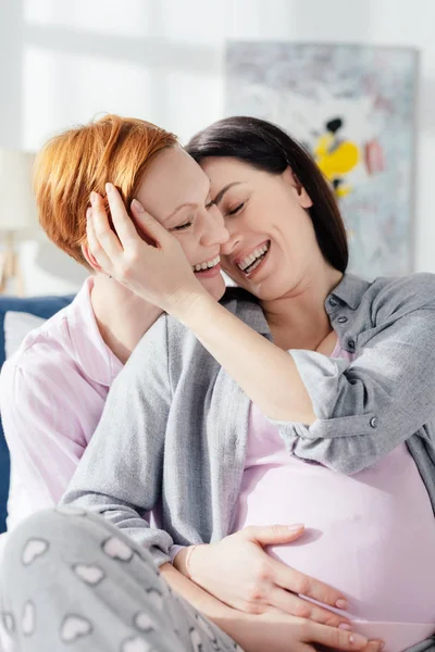 Rindo mulher grávida tocando rosto de namorada na cama — Fotografia de Stock
