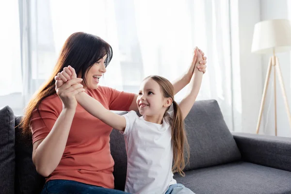 Felice madre giocare con sorridente figlia su divano a casa — Foto stock