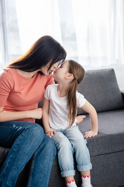 Mãe beijando filha no sofá na sala de estar — Fotografia de Stock