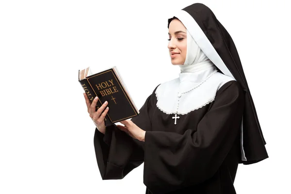 Hermosa monja sonriente sosteniendo la sagrada Biblia aislada en blanco - foto de stock