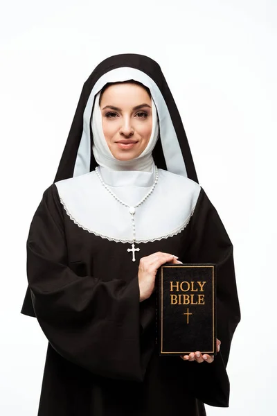 Monja sonriente sosteniendo la sagrada Biblia aislada en blanco - foto de stock