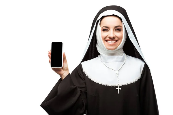 Cheerful nun presenting smartphone with blank screen isolated on white — Stock Photo