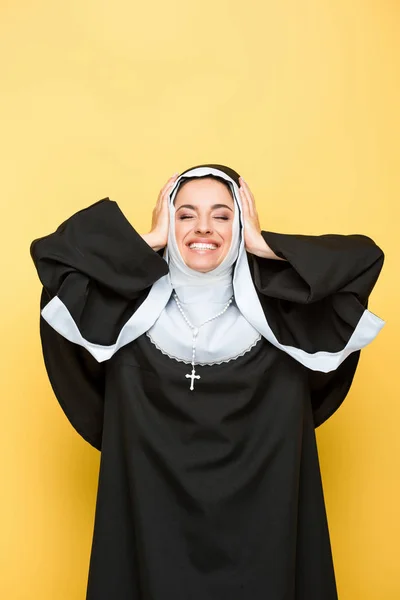 Beautiful happy nun with closed eyes, on yellow — Stock Photo