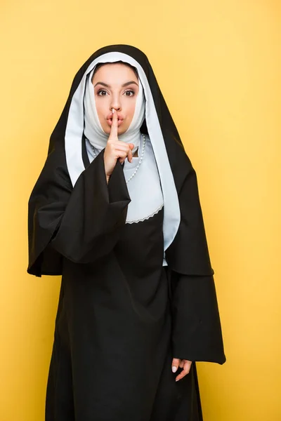 Beautiful nun showing silence symbol, on yellow — Stock Photo