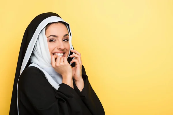 Fröhliche Nonne spricht auf Smartphone isoliert auf gelb — Stockfoto