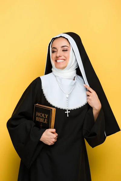 Belle religieuse souriante tenant sainte bible sur gris — Photo de stock