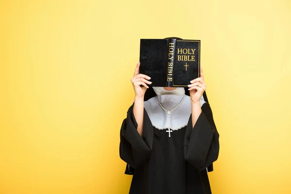 Young nun reading holy bible on grey — Stock Photo