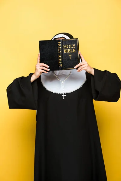 Young nun reading holy bible on grey — Stock Photo