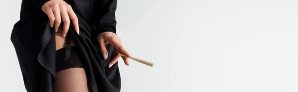 Панорамний знімок сексуальної черниці в панчохах, що тримає марихуану суглоба ізольовано на сірому — стокове фото