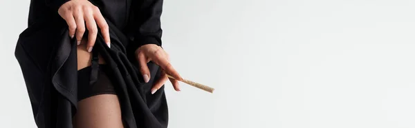 Panoramic shot of sexy nun in stockings holding marijuana joint isolated on grey — Stock Photo