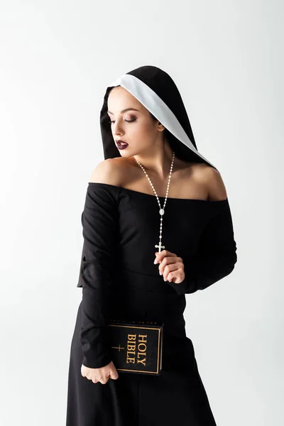 Monja sensual en vestido negro sosteniendo la Biblia aislada en gris - foto de stock