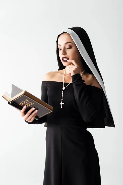 Passionate nun in black dress reading bible isolated on grey — Stock Photo