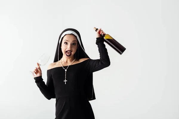 Excited sexy nun holding glass and bottle of wine isolated on grey — Stock Photo