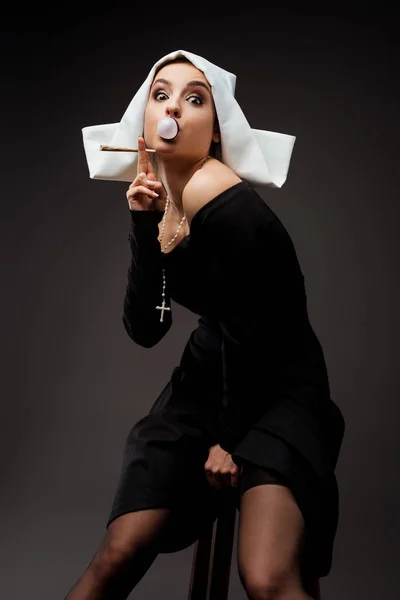Attractive sexy nun with bubble gum smoking marijuana joint on grey — Stock Photo