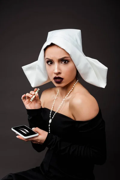 Эмоциональная сексуальная монашка с банкнотой в долларах и смартфоном с кокаином на серых линиях — стоковое фото