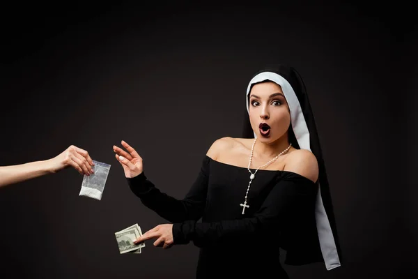 Shocked sexy nun with money buying plastic bag of cocaine isolated on grey — Stock Photo