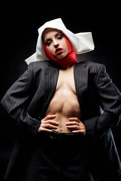 Naked fashionable sexy nun posing in black suit and red scarf, isolated on black — Stock Photo