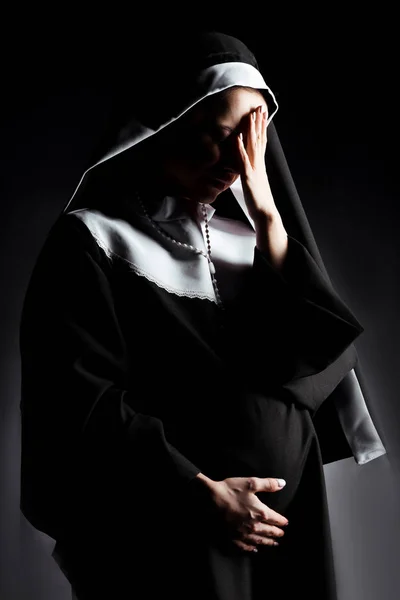 Sad crying pregnant nun touching tummy on grey — Stock Photo