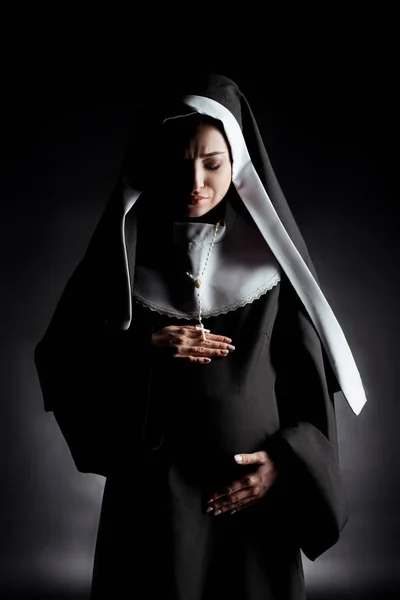 Upset pregnant nun touching belly on grey — Stock Photo