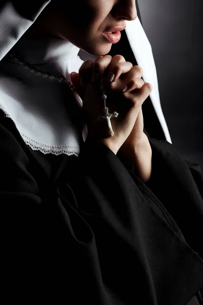 Cropped view of worried young nun praying with cross on grey — Stock Photo