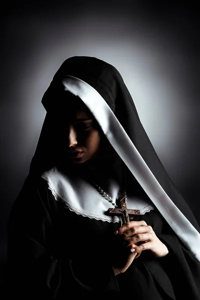 Belle jeune nonne triste tenant croix sur gris — Photo de stock