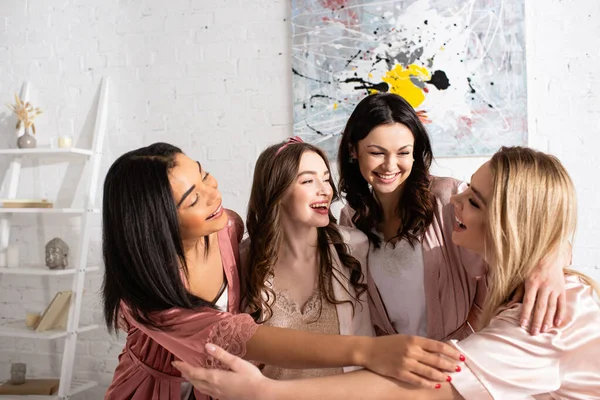 Multicultural friends laughing, hugging and looking at each other in room at bachelorette party — Stock Photo