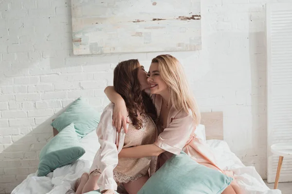 Frauen umarmen und lächeln bei Junggesellenabschied mit Kissen auf dem Bett — Stockfoto