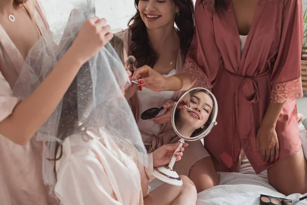 Multiethnic women putting makeup on bride in room at bachelorette party — Stock Photo
