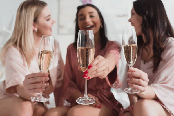 Enfoque selectivo de mujeres multiétnicas sosteniendo copas de champán y sonriendo en despedida de soltera — Stock Photo