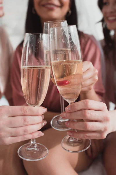 Vista recortada de mujeres multiétnicas tintineando con copas de champán en despedida de soltera - foto de stock