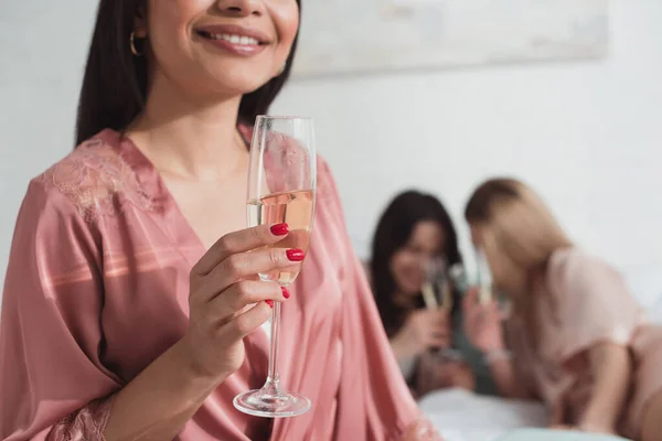 Vista ritagliata della ragazza afro-americana sorridente e con in mano un bicchiere di champagne — Foto stock